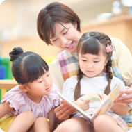 絵本を読み聞かせる保育士と園児