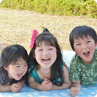 芝生で笑う3人の園児